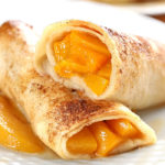 Peach Pie Enchiladas - It’s a bubbly, gooey, buttery, and peachy miracle! Something magical happens when fresh peaches, butter, and sugar meet flour tortillas.